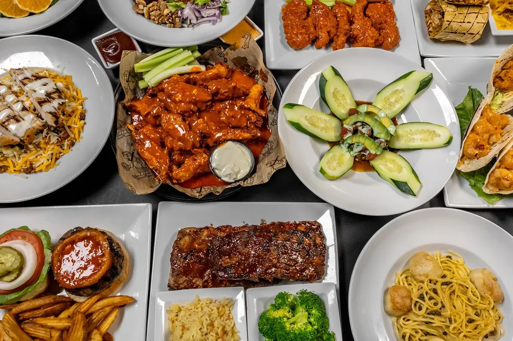 Overhead view of a diverse spread of restaurant dishes including ribs and tacos.