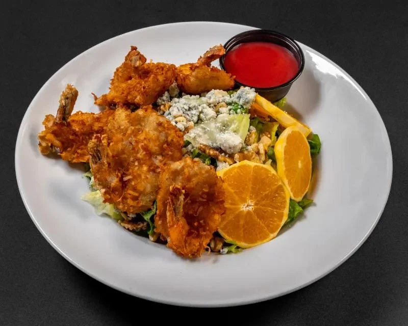 Coconut shrimp salad with blue cheese, walnuts, orange slices, and red sauce.