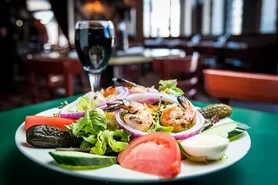 Close-up of grilled shrimp salad on teal table in a restaurant.