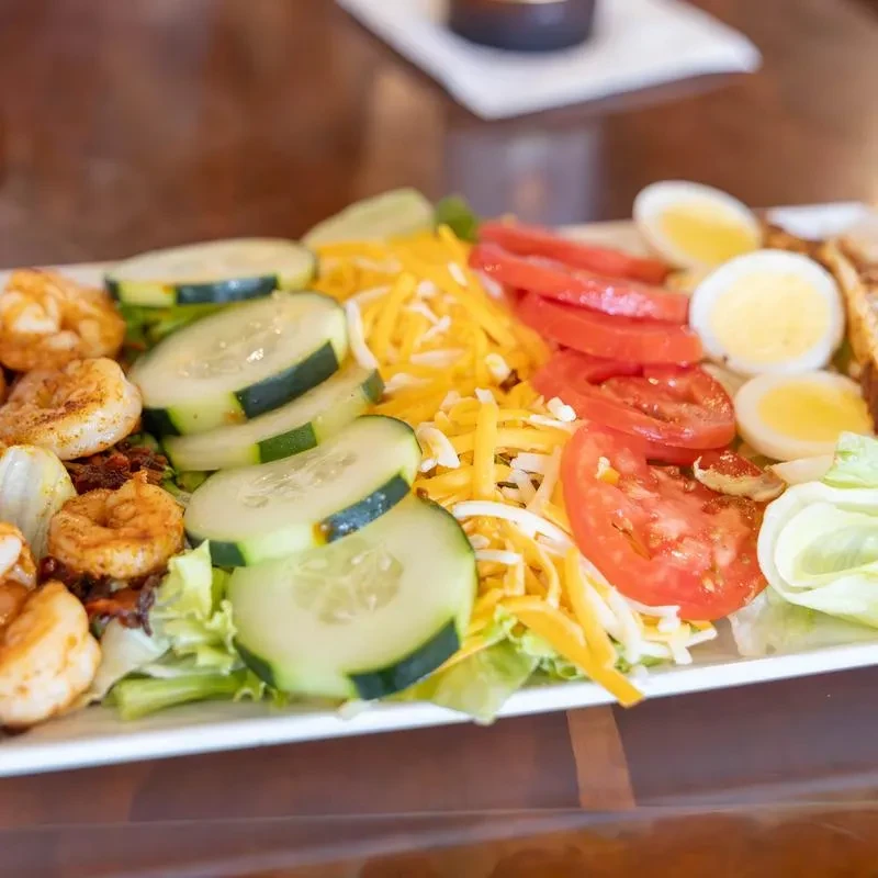 Colorful salad with shrimp, cucumber, cheese, tomatoes, and eggs.