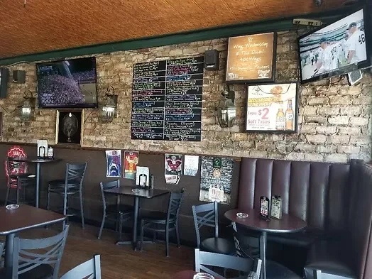 Rustic sports bar interior with TVs, chalkboard menu, and booth seating.