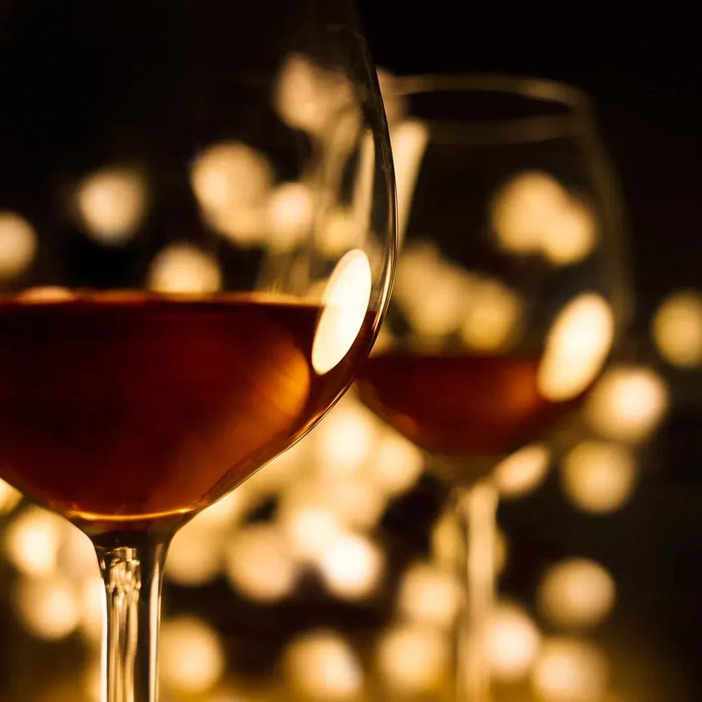 Two glasses of reddish-brown liquid, one sharp, one blurred, bokeh.