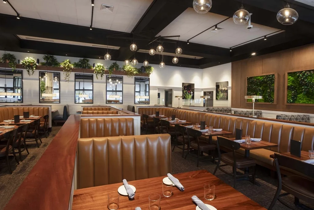 Modern restaurant interior with caramel booths, dark tables, and natural decor.