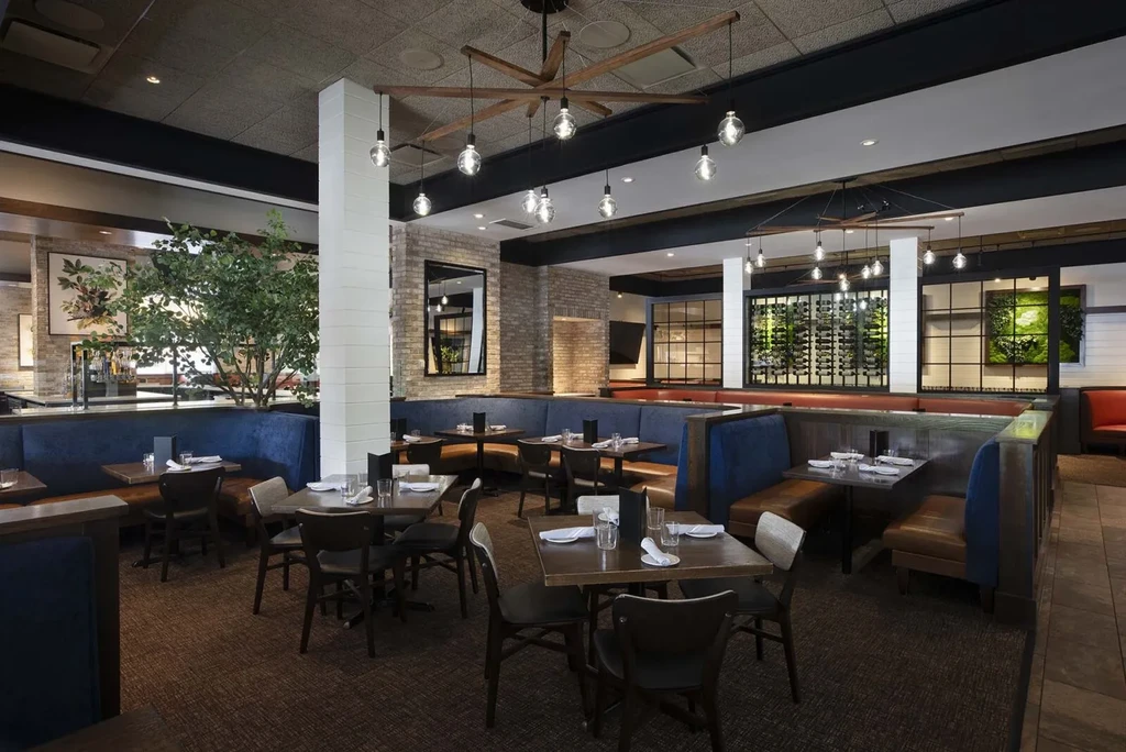Modern restaurant interior with blue booths, set tables, and varied decor.