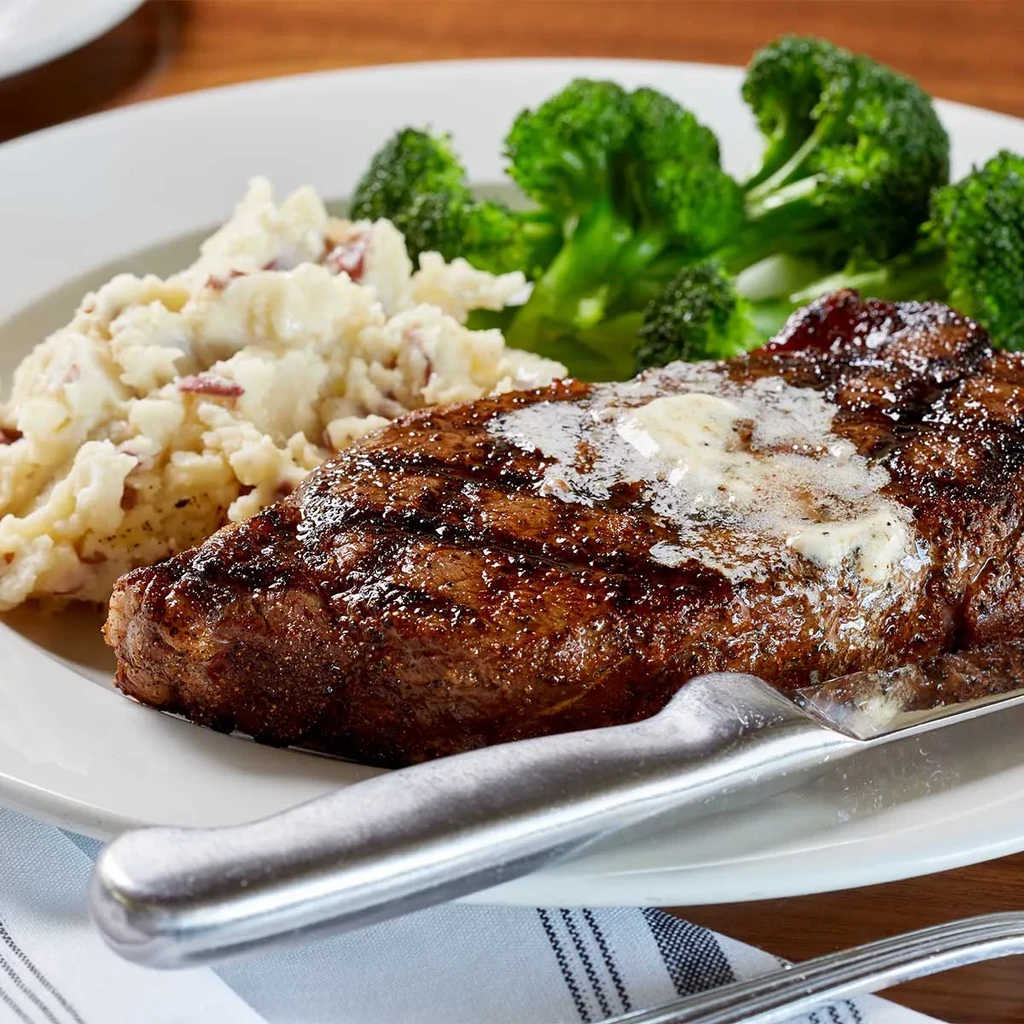 Grilled steak with melting butter, red skin mashed potatoes, and broccoli.