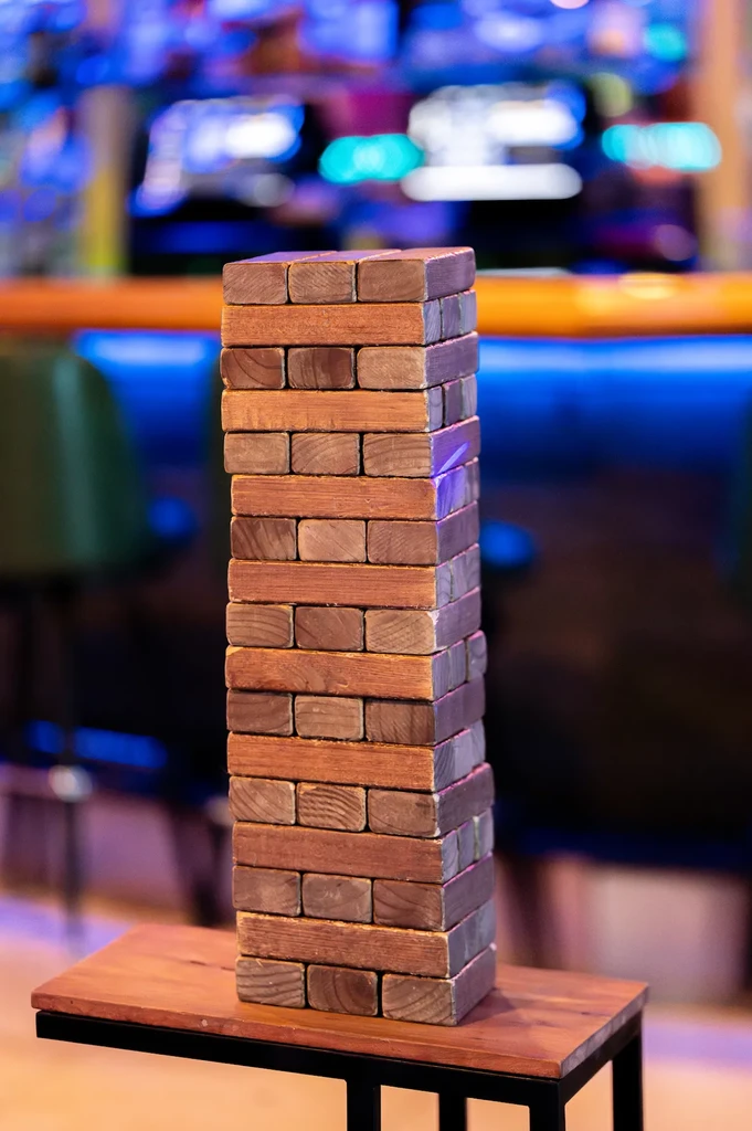 Jenga-style wooden block tower against a blurred colorful background.