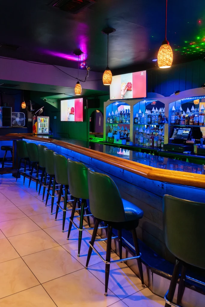 Empty modern bar with blue LED lighting and green bar stools.