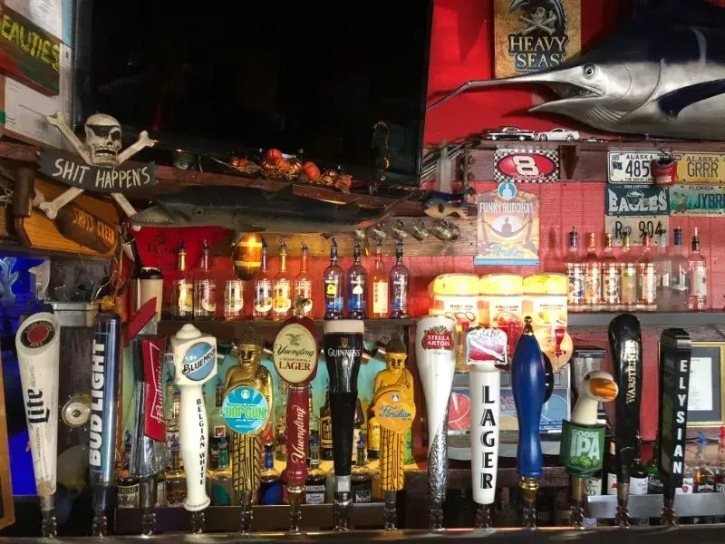 Row of beer taps in a densely decorated, quirky, nautical-themed bar.