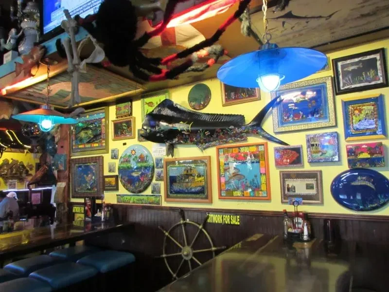 Eclectic tropical restaurant: yellow walls, fish art, large metallic fish.