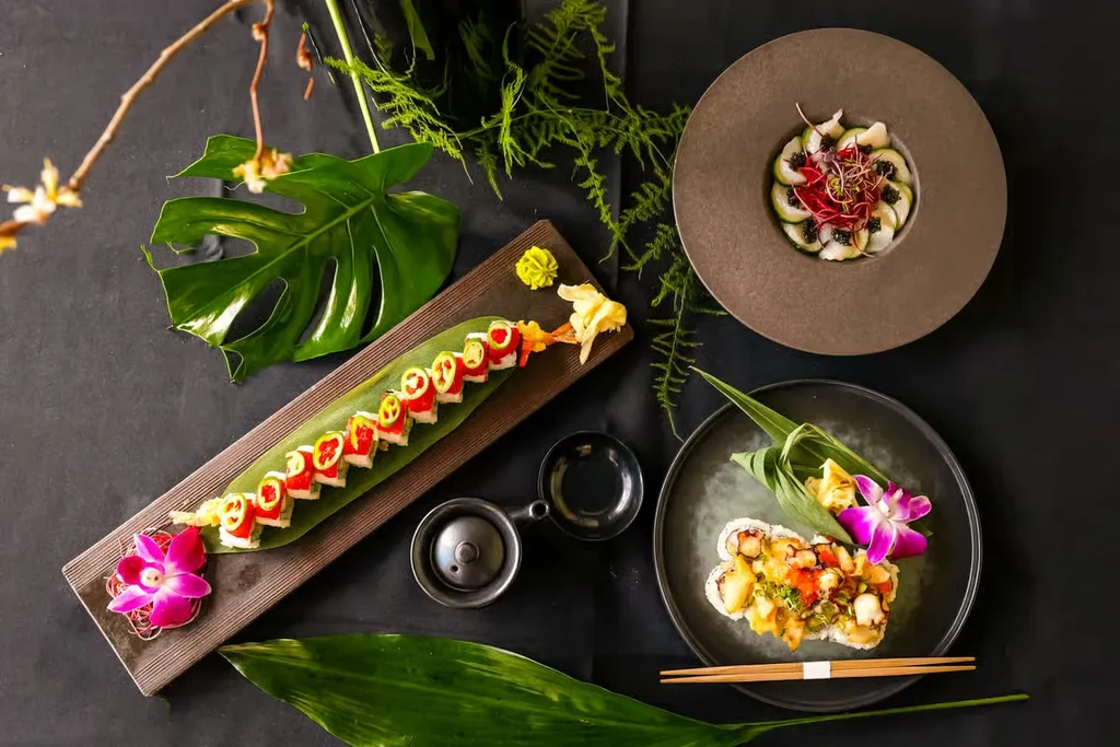Top-down shot of three artfully arranged Japanese sushi and sashimi dishes.