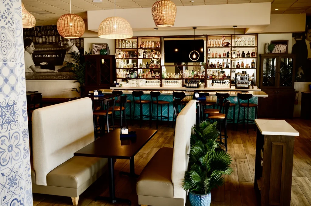 Teal-tiled bar, beige booths, and black and white mural in restaurant interior.