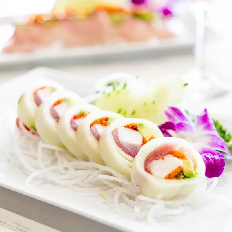 Maki sushi rolls with tuna, white fish, avocado, and purple orchid.