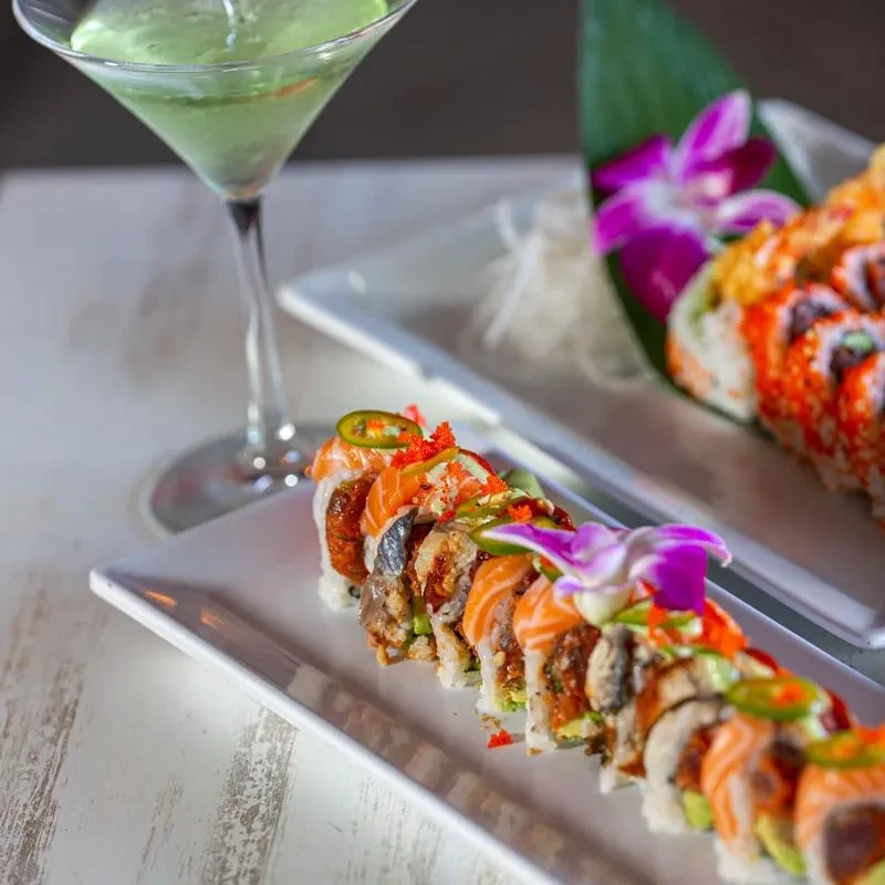 Meticulously arranged sushi rolls with colorful toppings and a green martini.