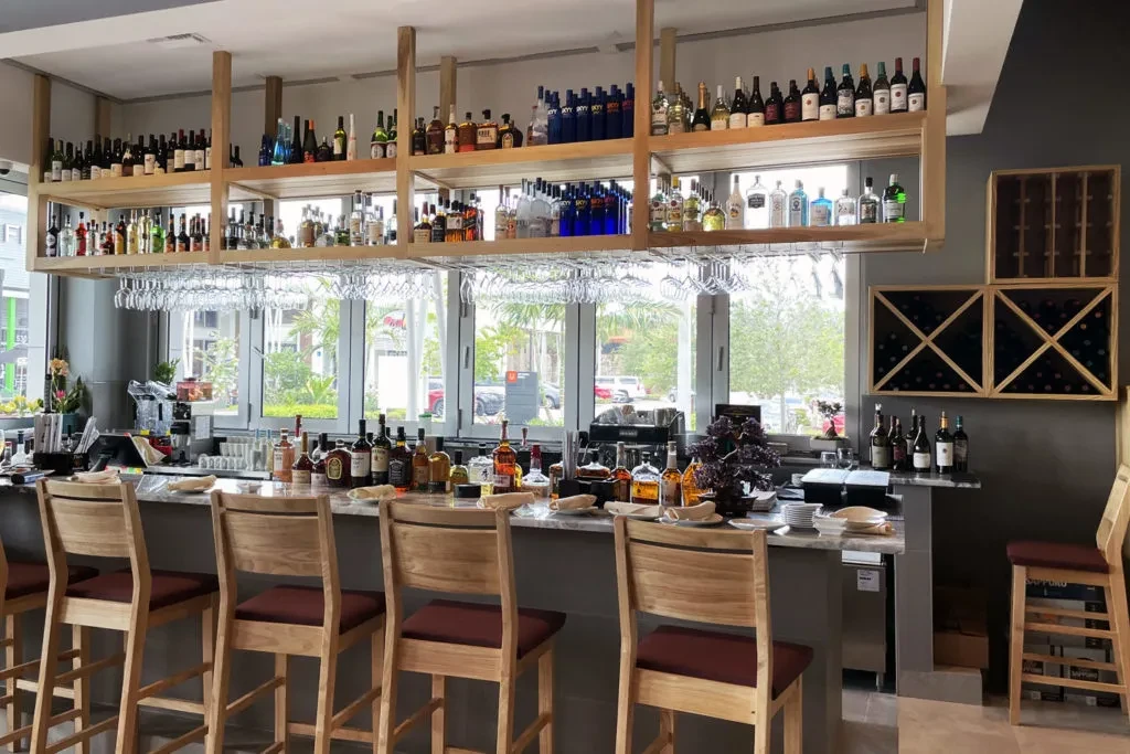 Contemporary bar interior with extensive liquor display and marble counter.