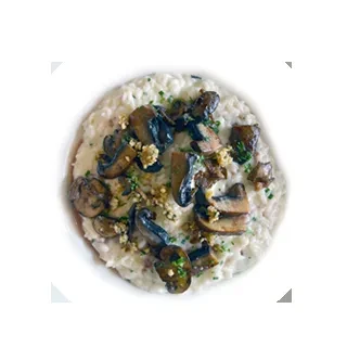 Top-down view of creamy risotto topped with sautéed mushrooms and herbs.