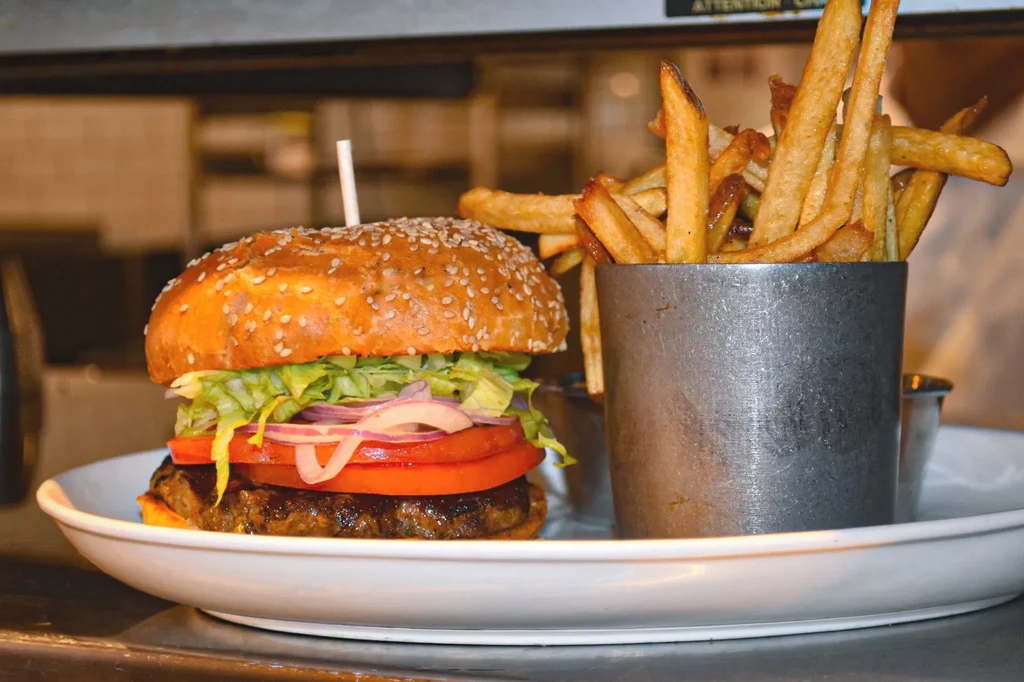 Close-up of a gourmet burger and golden french fries on a plate.