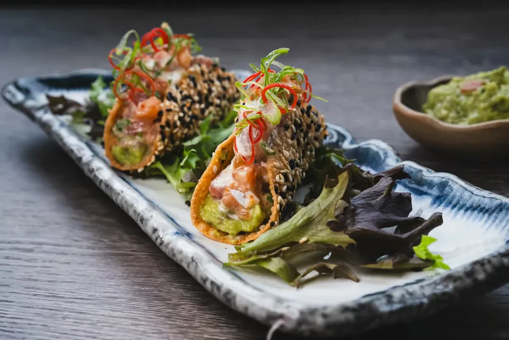 Two crispy sesame-crusted salmon tacos with avocado and chili.