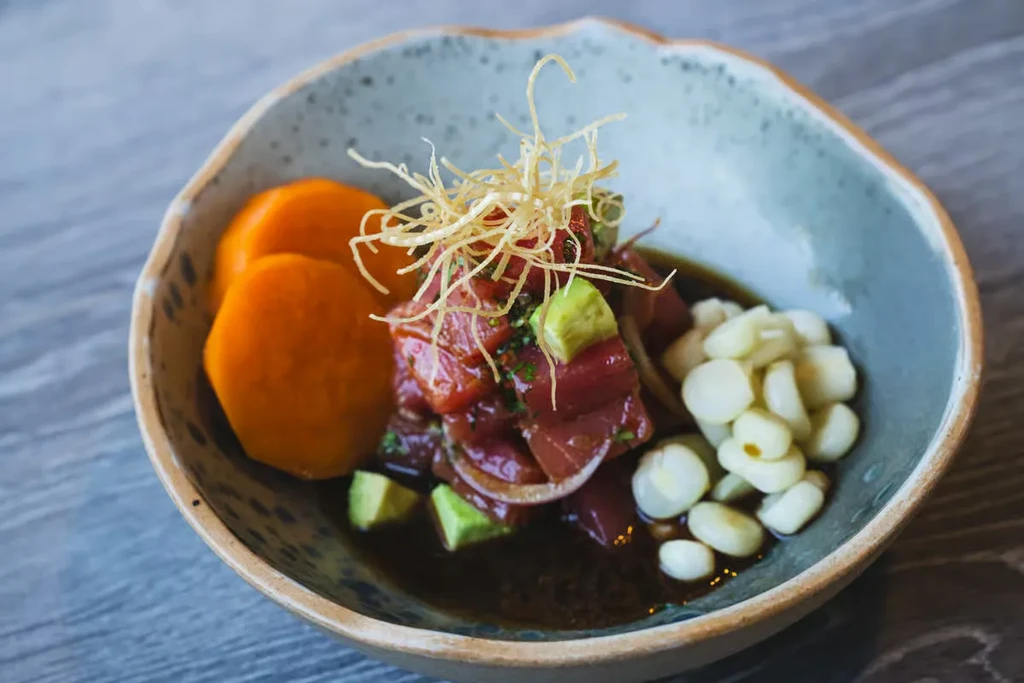 Red tuna ceviche with avocado, sweet potato, corn, and crispy garnish.