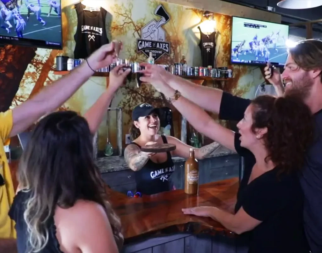 Group toasting with bartender at Game of Axes bar.