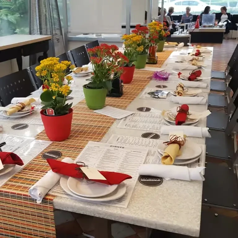 Restaurant dining table set for dinner with flowers and menus.
