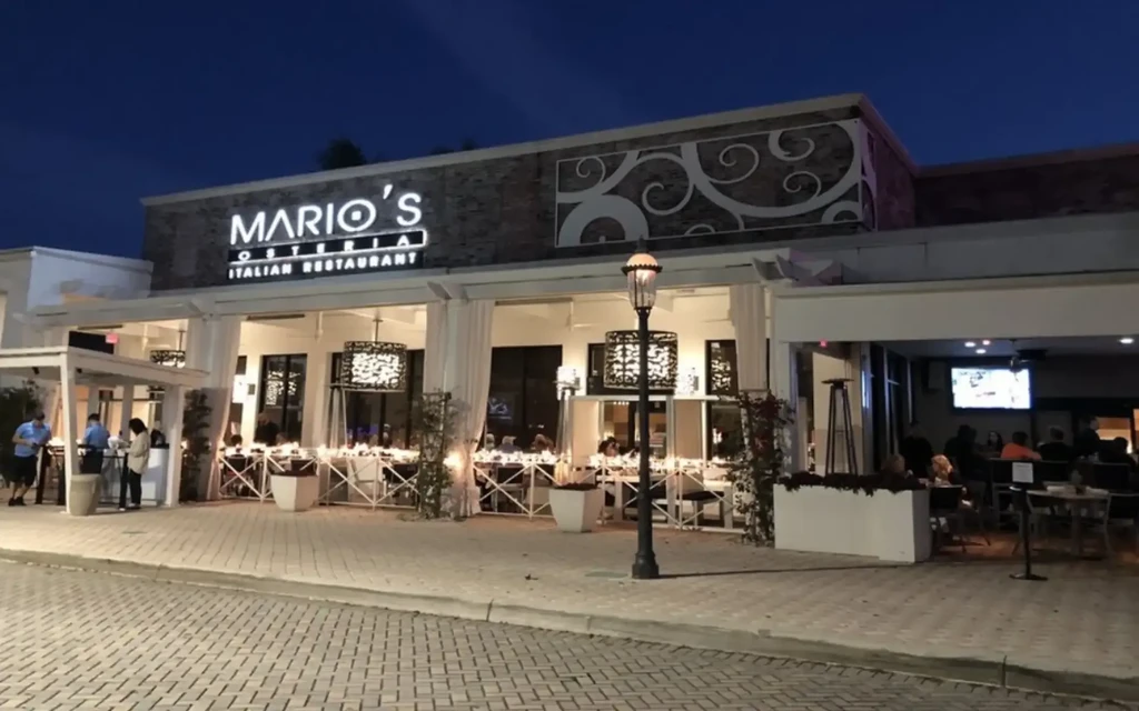 Mario's Osteria exterior at night, with glowing sign and outdoor dining.