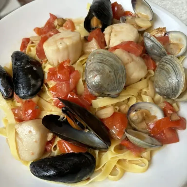 Seafood pasta with scallops, mussels, clams, and diced tomato sauce.