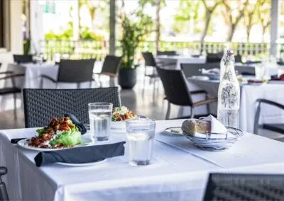 Set table with food, drinks, and bread in an outdoor restaurant patio.