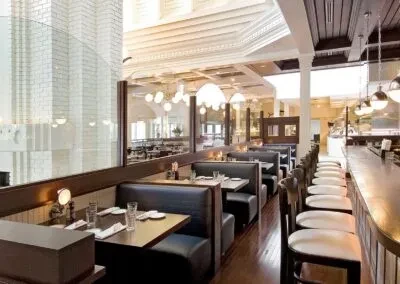 Empty modern restaurant interior with dark booths and a long bar.