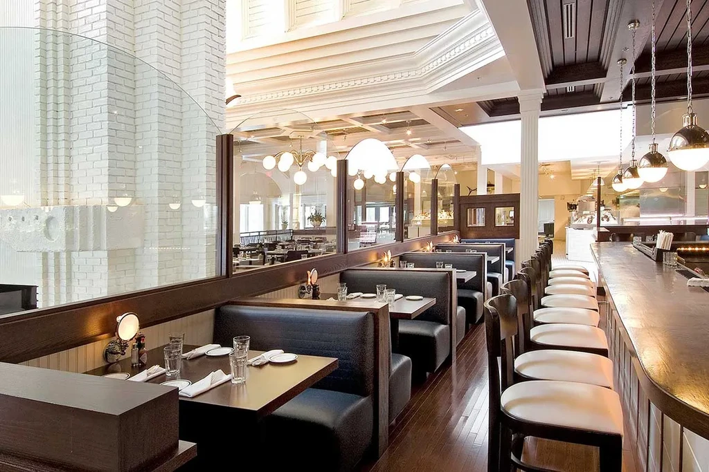 Elegant restaurant interior with dark dining booths and a curved wooden bar.