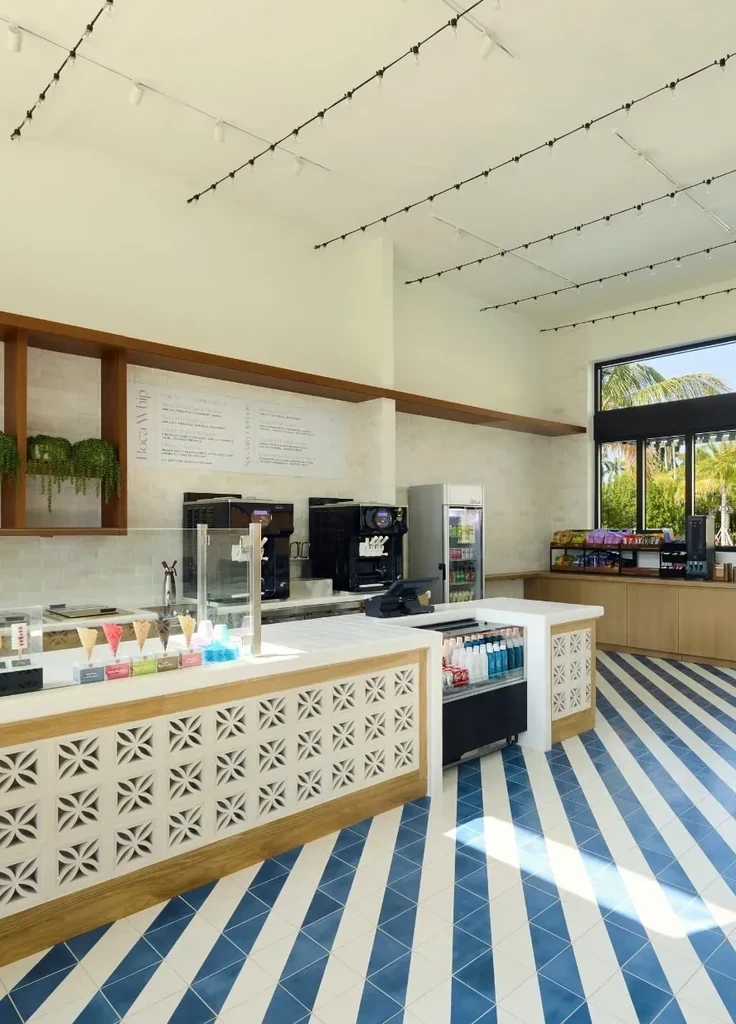 Bright, modern ice cream parlor counter with colorful cones and soft-serve machines.