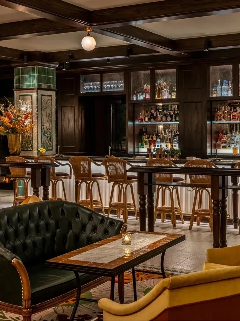 Elegant bar lounge with dark wood, stocked bar, and tufted sofa.