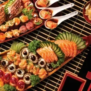 Overflowing sushi and sashimi boat platter with various Japanese dishes.