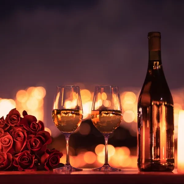 White wine glasses, bottle, and red roses in elegant setting.