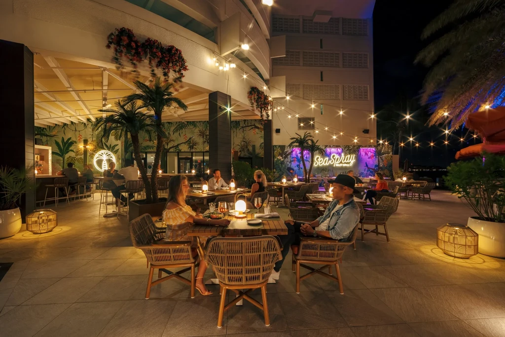 Sea Spray Inlet Grill, tropical restaurant, lit at night with diners.
