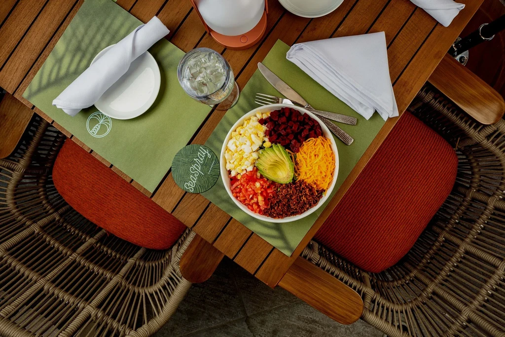 Overhead view of a vibrant salad bowl on a neatly set outdoor table.