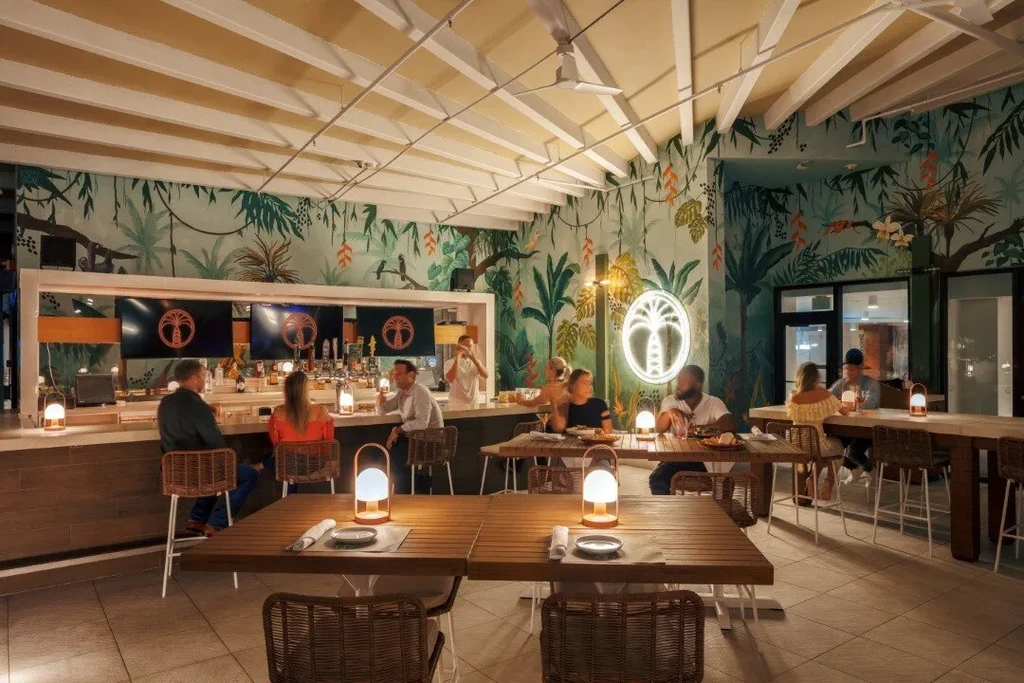 Vibrant tropical restaurant and bar with jungle mural and patrons.