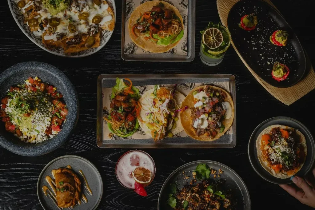 Overhead view: diverse Mexican dishes, including tacos, nachos, and cocktails.