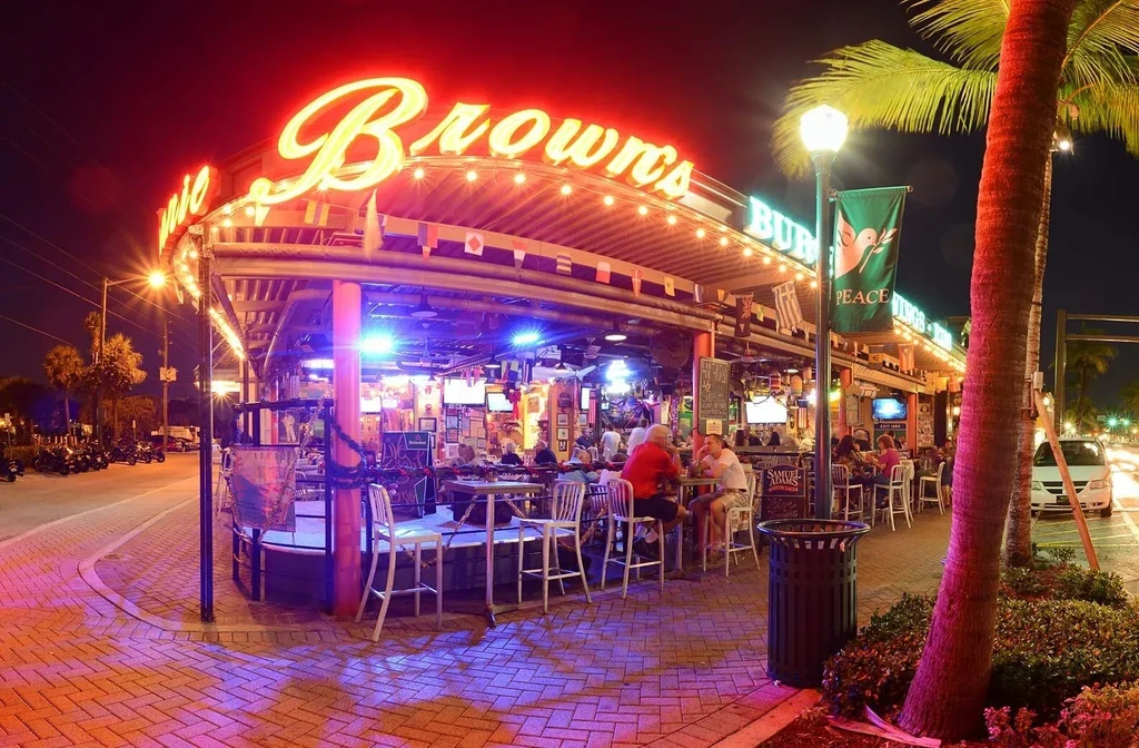Glowing red neon sign illuminates Browns restaurant patio at night.