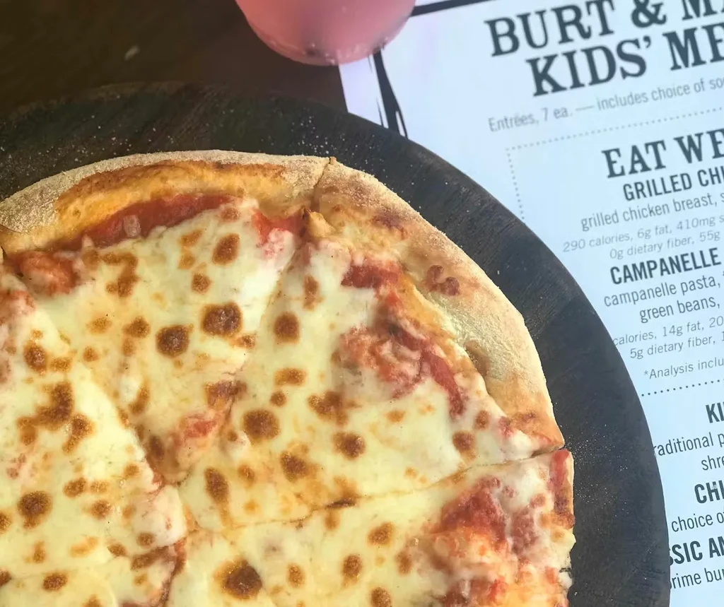 Close-up of a bubbly cheese pizza on a dark rustic serving board.