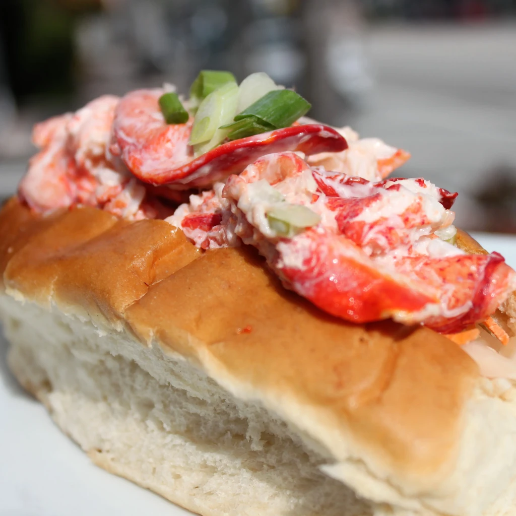 Close-up of a golden-brown lobster roll with creamy lobster and chives.