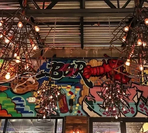 Colorful graffiti mural with "BAR" and a red lobster in a bar.
