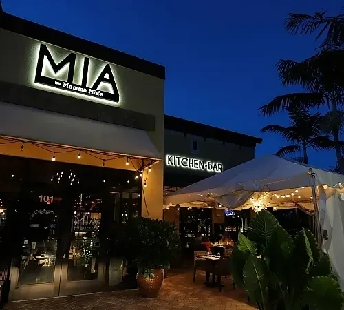 Illuminated 'MIA by Mamma Mia's' restaurant exterior with tented outdoor seating at night.