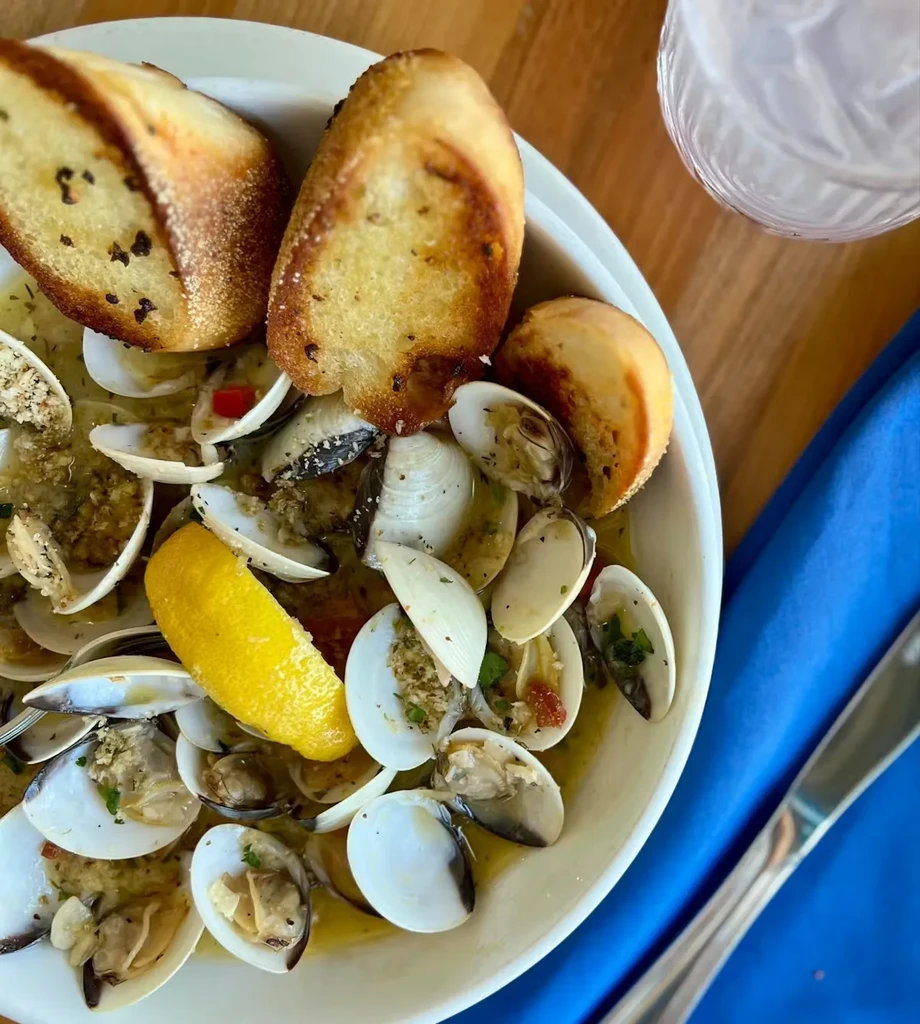 Steamed clams in light broth with bread and a lemon wedge.