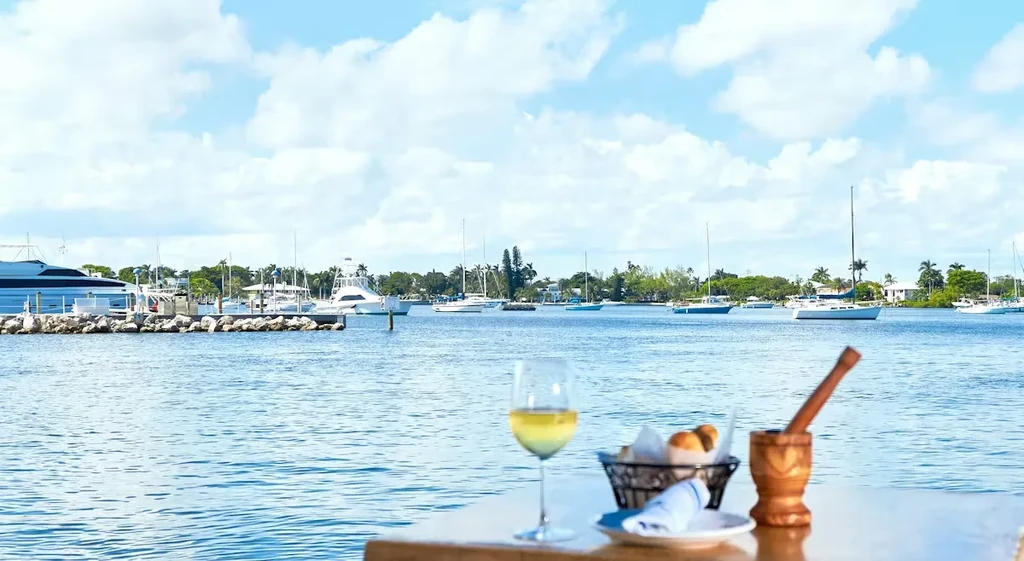 Outdoor dining table with wine, bread, mortar, overlooking a harbor.