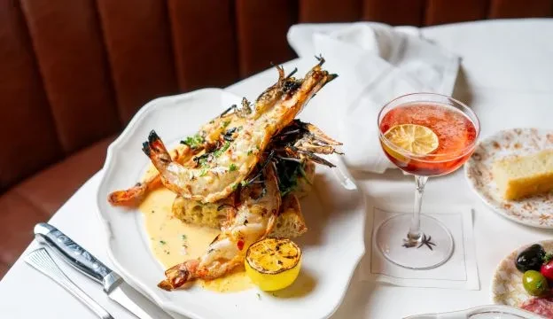 Grilled prawns on toast, cocktail, and dessert in an upscale restaurant.