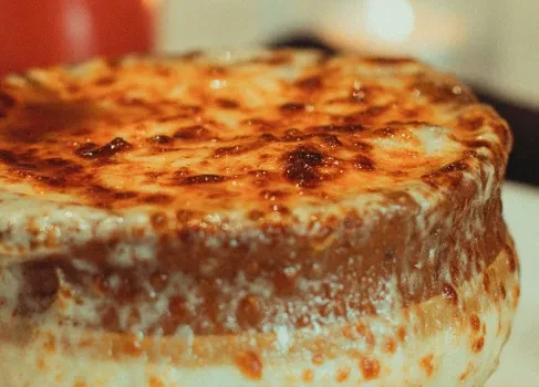 Close-up of golden-brown, bubbly cheese topping a baked dish.