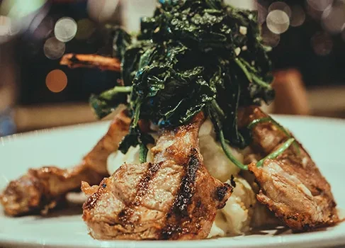 Grilled chops on mashed potatoes with dark green vegetables.