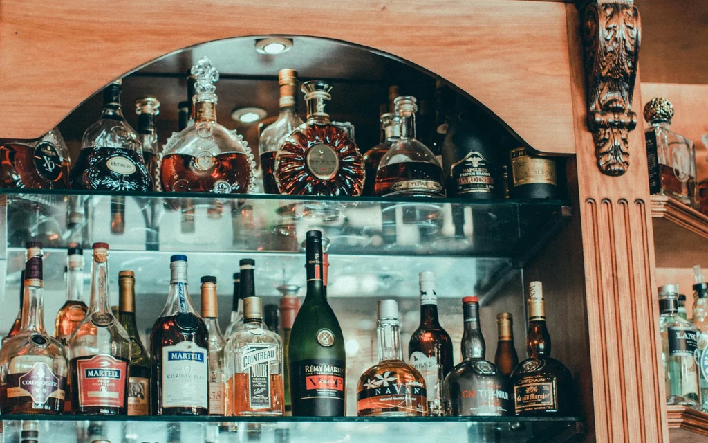 Premium cognacs, brandies, and liqueurs in an ornate liquor cabinet.