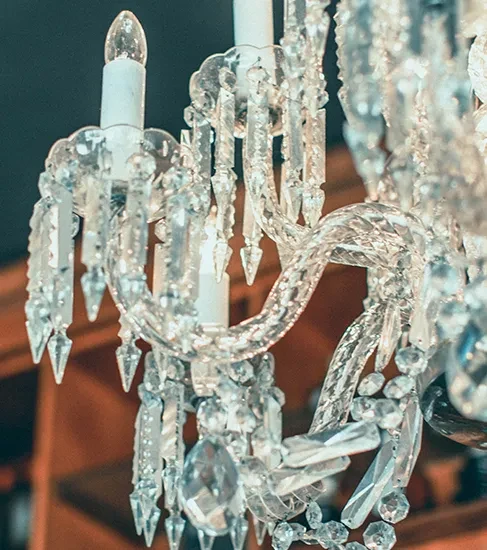 Close-up of a tiered crystal chandelier with glowing faux candle bulbs.