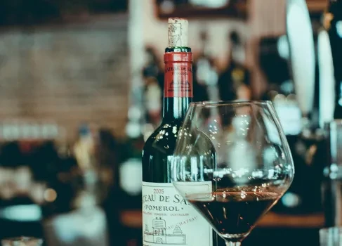 Close-up of 2005 Pomerol red wine bottle and partially filled glass.